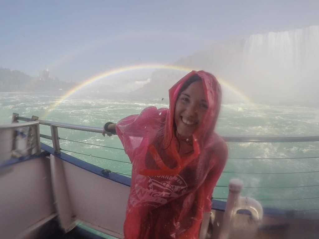 Brooke with her rain poncho on in front of Niagara Falls and a double rainbox on Hornblower Niagara Cruise