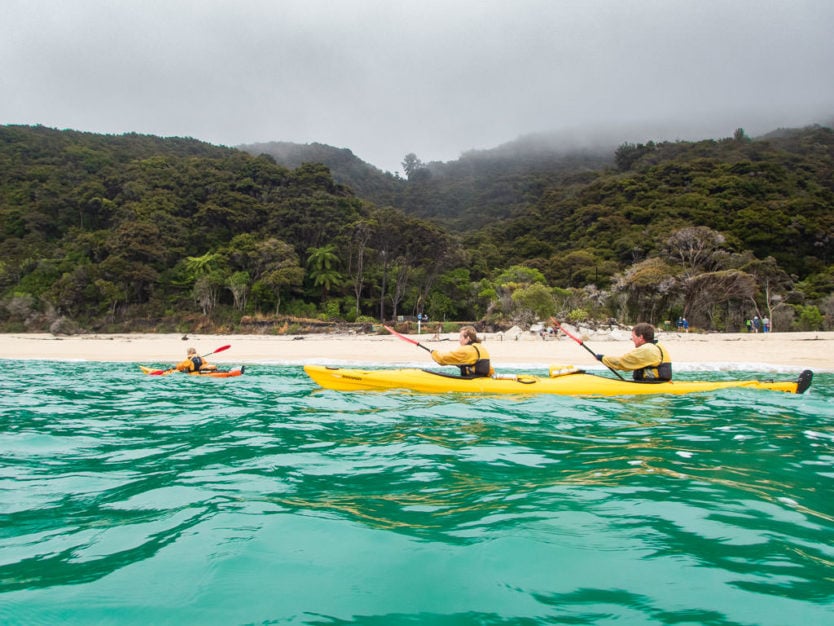 kayakers paddling along the coast of Onetahuti Bay